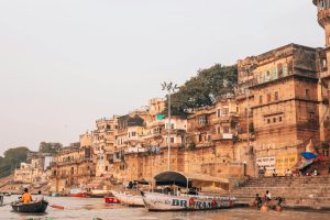 Picturesque view of Varanasi ghats along the Ganges River with bustling boats and ancient architecture.